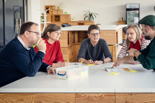 Förderberater sitzen diskutierend um einen Tisch