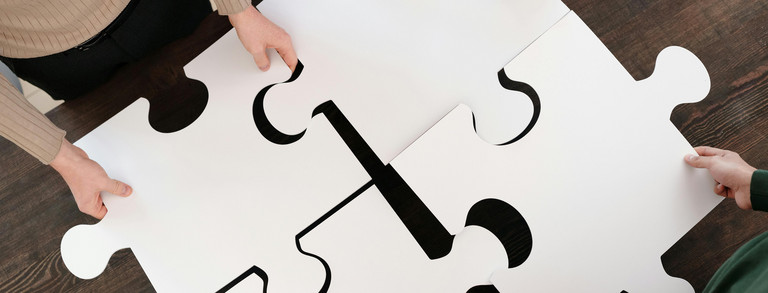 Vier Menschenhände halten vier Puzzleteile