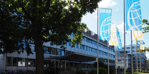 Gebäudeansicht des DAAD-Haupthauses in Bonn, blaue DAAD-Flaggen davor
