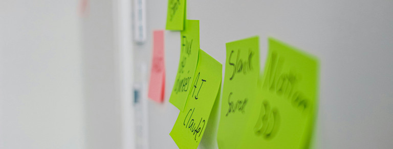 Grüne Haftnotizen mit handschriftlichen Notizen an einem Board