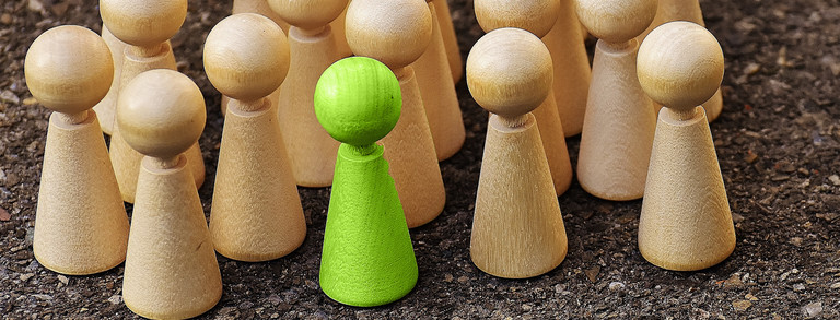 Hölzerne Spielfiguren, eine grün hervorgehoben